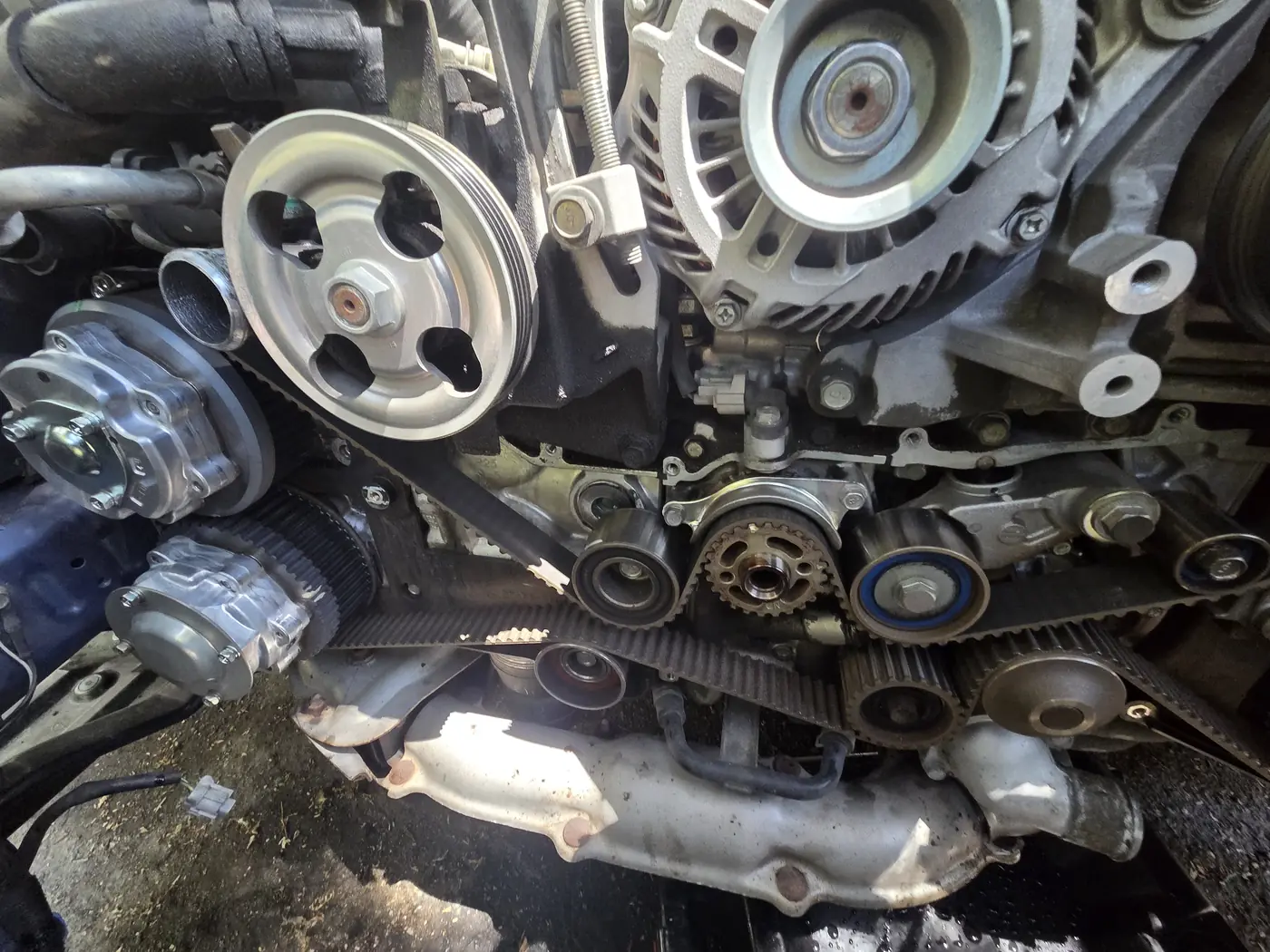 The front of an engine with the drive belt, pulleys and a toothed timing belt exposed