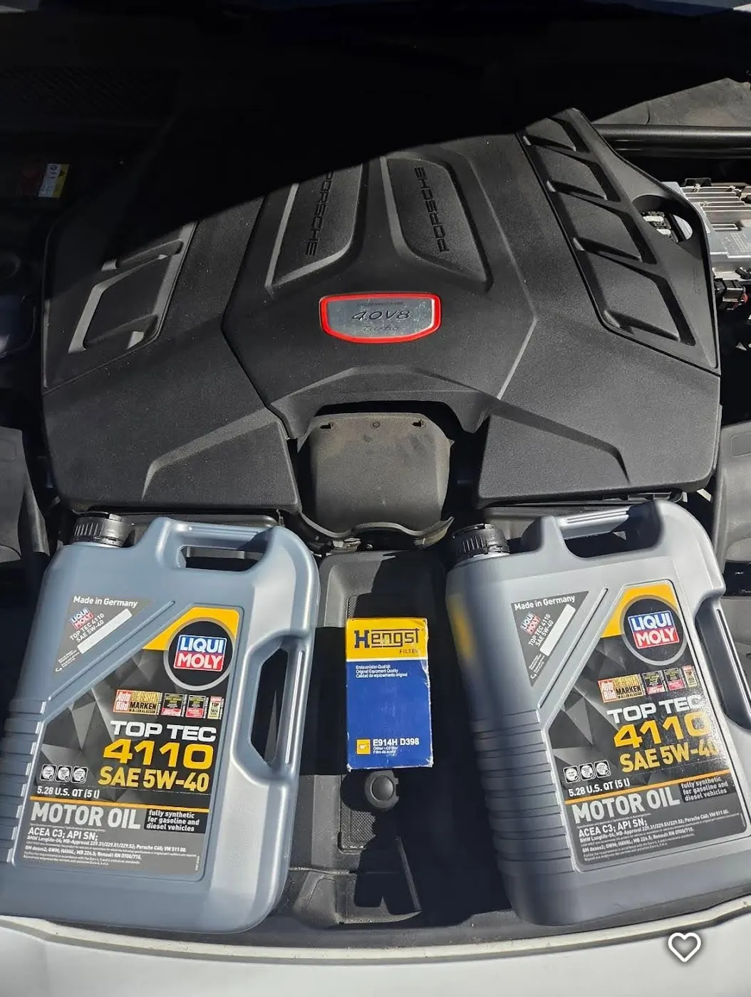 Two jugs of 5W-40 motor oil and a boxed oil filter resting on an engine cover