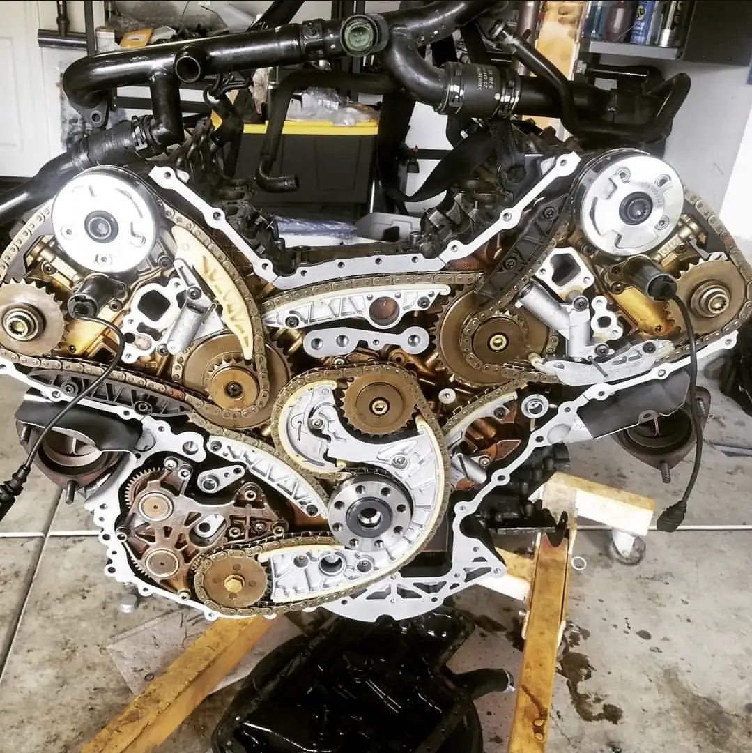 A V8 engine on a stand with its timing chains, cam sprockets and chain guides all exposed